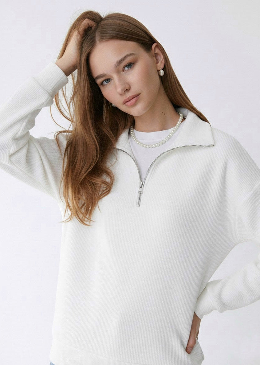 Woman wearing a white sweater with a plain background