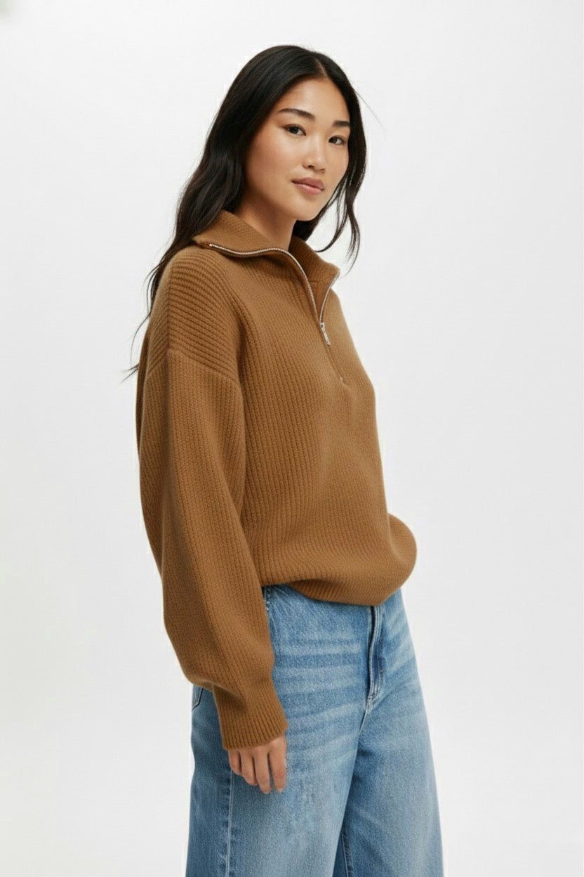 Woman wearing a brown sweater and blue jeans on a white background